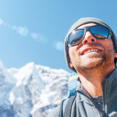 Portrait Of Smiling Hiker Man On Taboche 6495m And Cholatse 6440m Peaks Background With Trekking Poles, Uv Protecting Sunglasses. He Enjoying Mountain Views During Everest Base Camp Trekking Route.